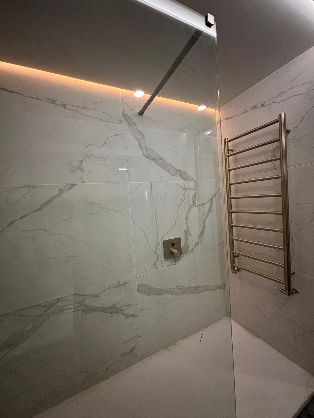 Elegant wet room featuring white subway tiles and brass hardware